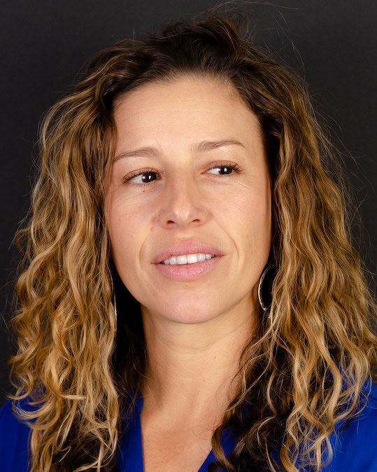 Headshot of a an atractive woman with brown wavy hair. 