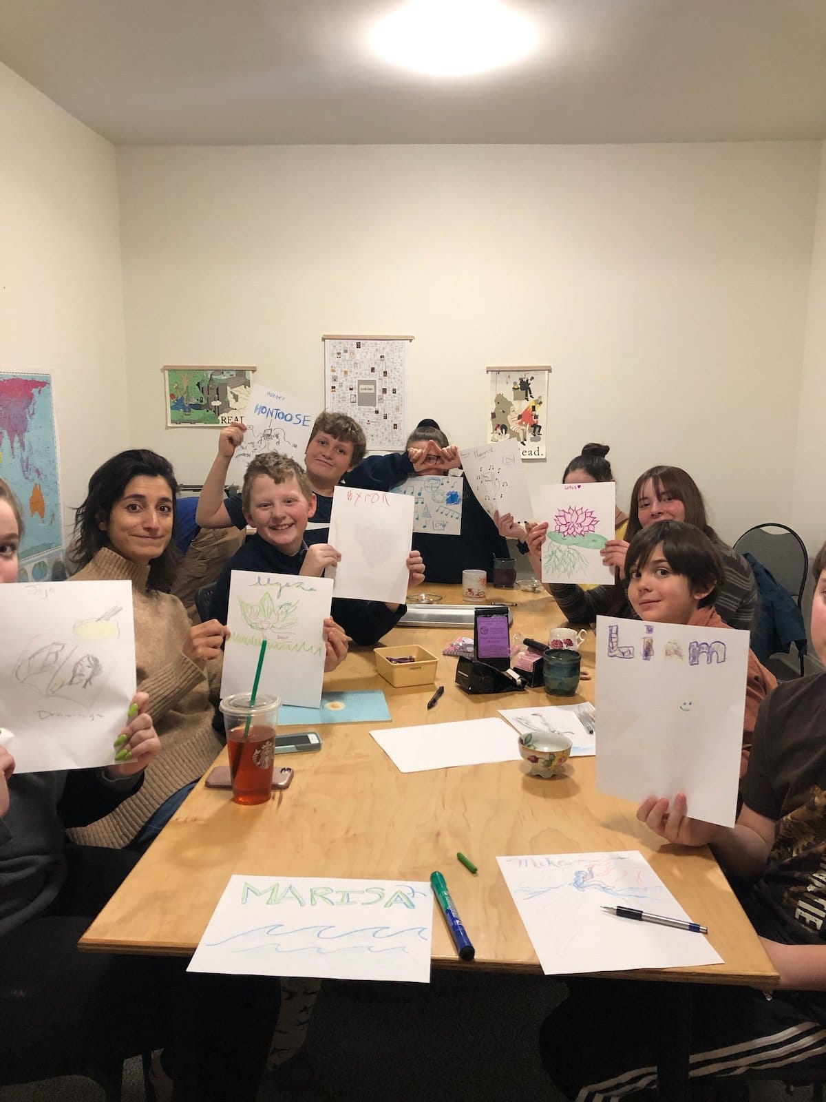 A table with children showing their artwork.